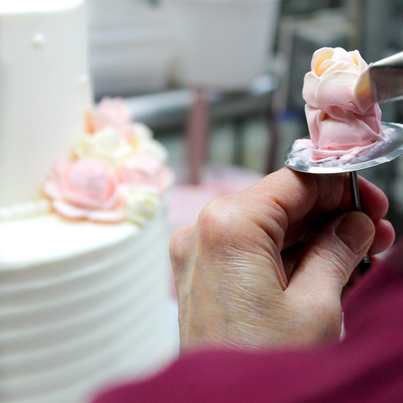 Our owner, Kathy Battis, creating an icing flower for a wedding cake.